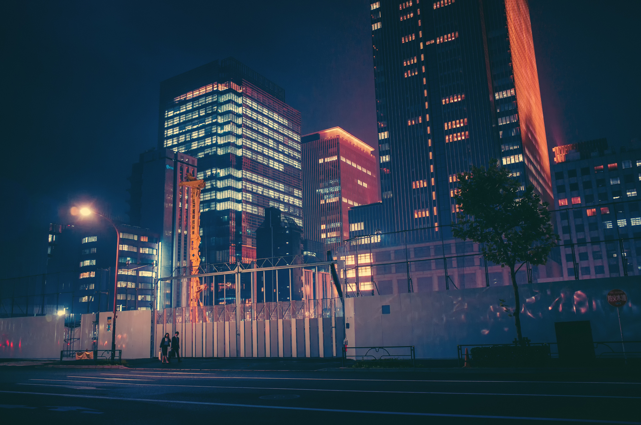 a_city_at_night_with_a_fence_and_buildings