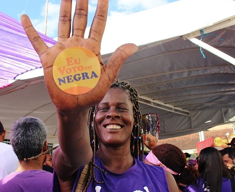 mulher com um adesivo colado na mão escrito voto em negra